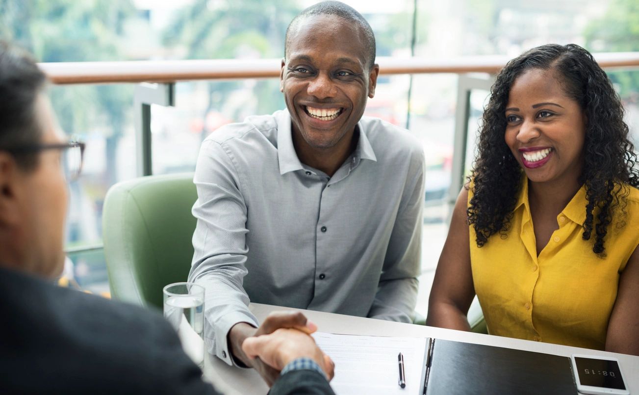 Two professionals shaking hands in a business setting, smiling warmly.